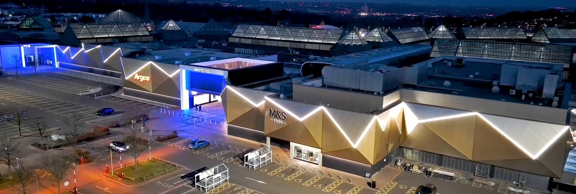 Shopping centre lit up at dusk from the air