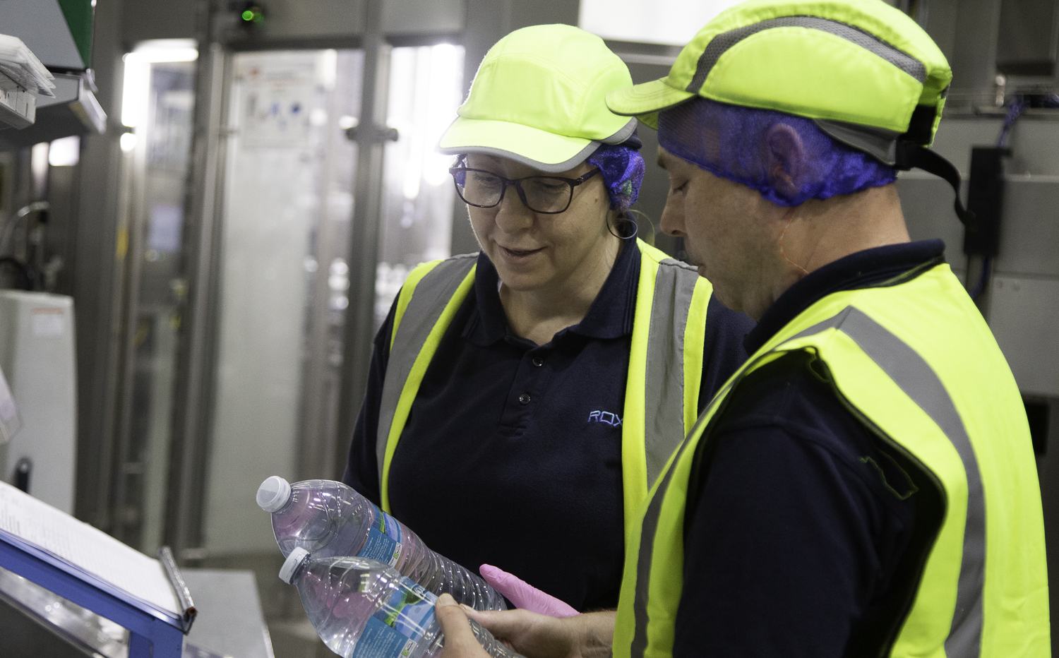 Two staff checking bottles during quality control