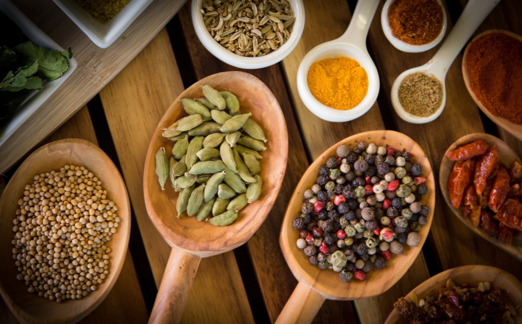 Whole spices in wooden spoons photographed from above