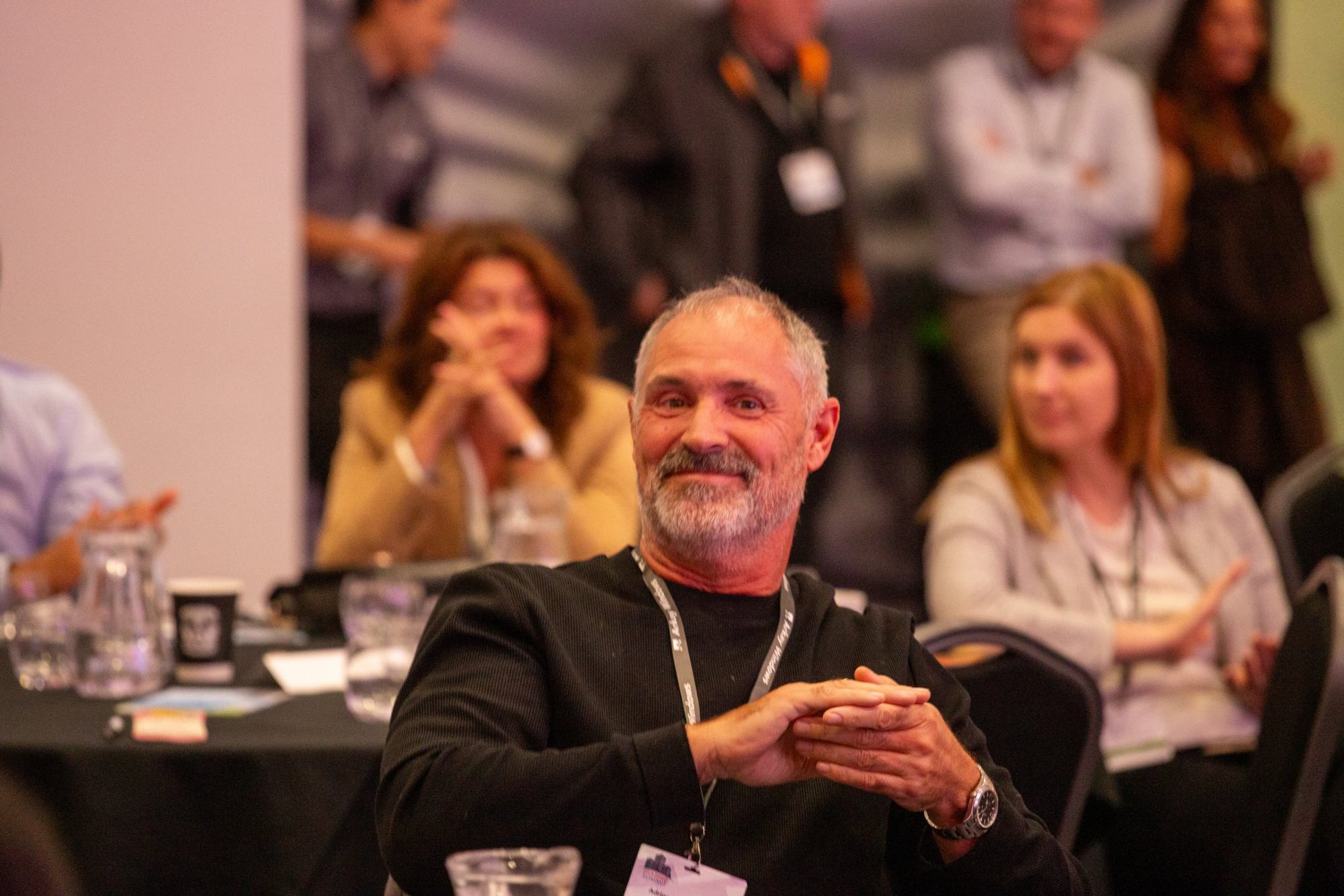 Smiling delegate applauding at the Glazing Summit