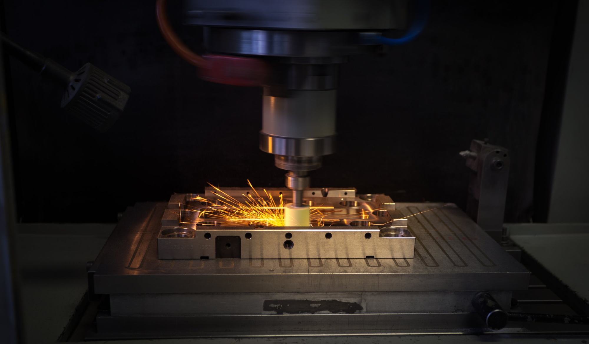 Sparks flying from a CNC machine cutting a steel block