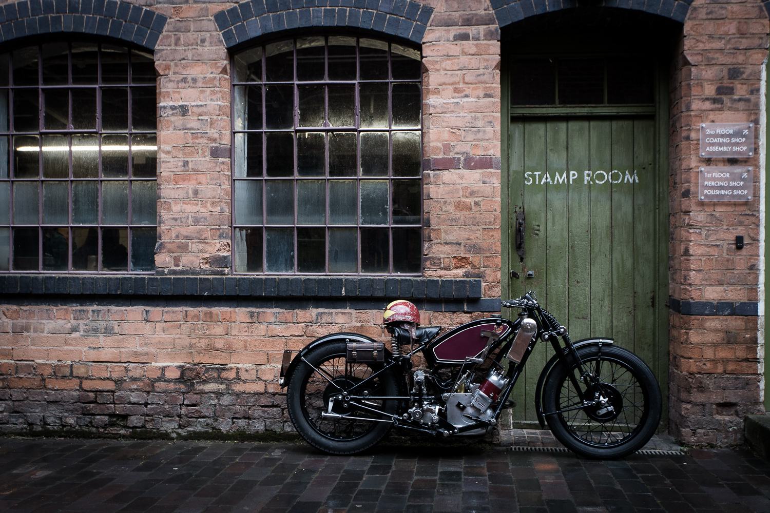 Vintage motorbike against a brick factory wall and green door