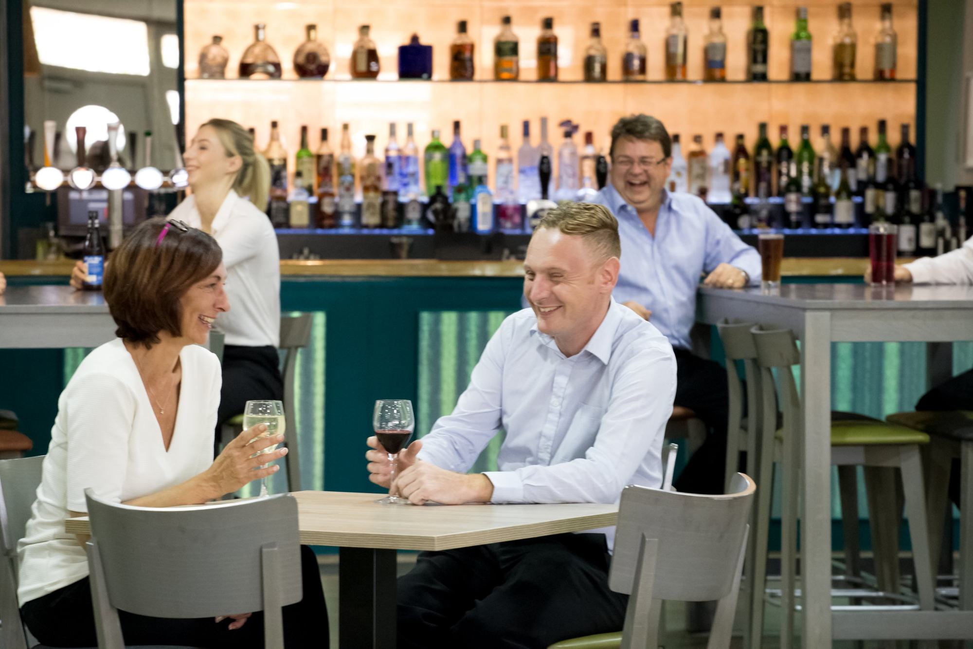 Colleagues laughing over drinks in a venue bar